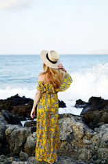 Young beautiful woman in a hat and yellow maxi dress, sunny day, freedom concept, vacation, tropical nature