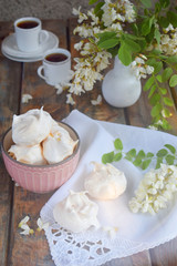 Obraz na płótnie Canvas Meringues cookies and cup of coffee. Homemade Meringue kisses drops with acacia flowers. Vintage photo. Copy space