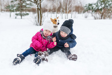 Fototapeta na wymiar Cute children and dog playing in snow.