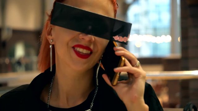 Fashion pretty red hair stylish woman with black sunglasses talks with here friend by mobile phone close-up