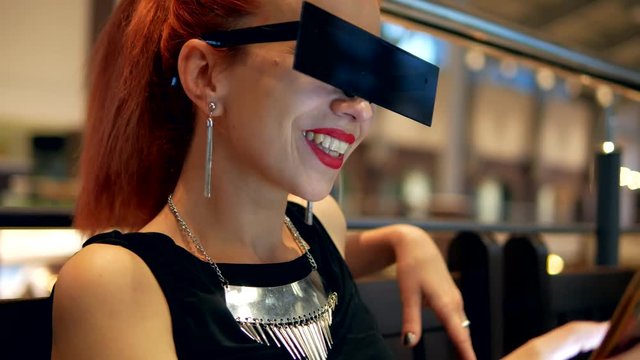 Stylish red hair posh woman watches mobile phone news and smiling in mall indoor close-up