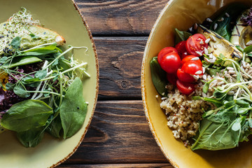 flat lay with vegetarian salads with spinach and sprouts served in bowls on wooden tabletop