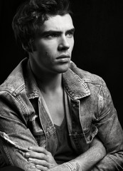 Obraz premium Black and white portrait of young handsome man on black background.