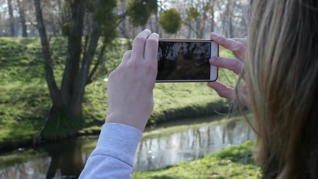 Young woman blogger take smartphone mobile picture of nature park