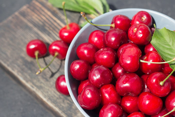 ripe red berries cherries in a round plate on a dark wooden background close-up