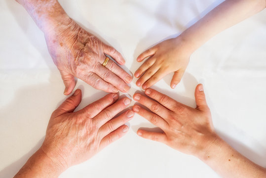 H&auml;nde mehrerer Generationen ber&uuml;hren sich die Finger.