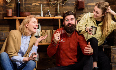 Friends have fun, speaking and drinking in wooden interior. Man and ladies on happy faces discussing and drinking. Friends for tea or wine in living room laughing and have fun. Communication concept