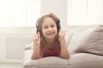 Pretty female kid listening to music in headphones