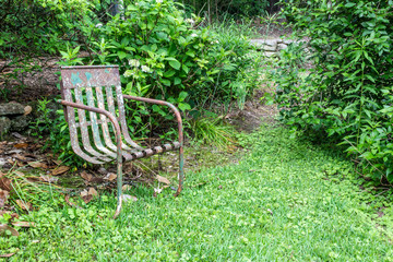 Old metal chair, green ground cover, copy space, death grief absence concept, horizontal aspect