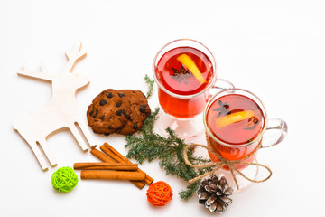 Winter beverage concept. Glasses with mulled wine or hot drink near wooden deer decoration on white...
