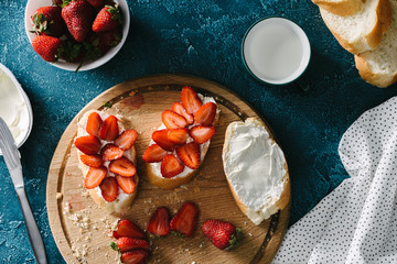 top view of summer meal with cream cheese and strawberries on bread pieces