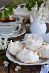 Meringues cookies and cup of coffee. Homemade Meringue kisses drops with acacia flowers. Vintage photo. Copy space