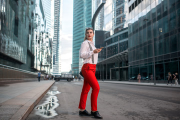Fototapeta na wymiar Business Woman With Phone Near Office. Portrait Of Beautiful Smiling Female In Fashion Office Clothes Talking On Phone While Standing Outdoors. Phone Communication. High Quality Image