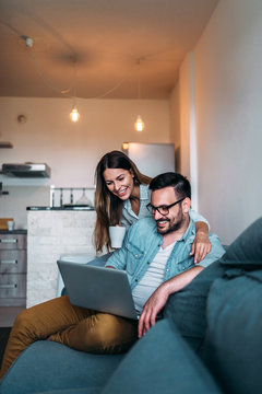 Couple using laptop while sitting on the sofa.