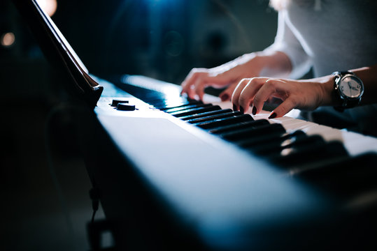 Close-up image of a female hands playing piano synhtesizer.