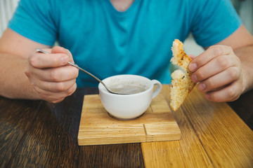 man eating soup in cafe. hold bread in other hand