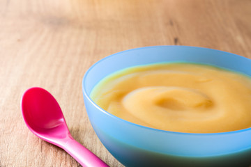 Baby food: colorful bowl of fruit puree on wooden table. Copyspace