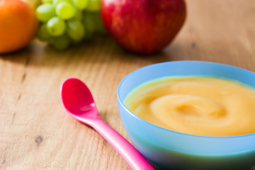 Baby food: colorful bowl of fruit puree on wooden table. Copyspace