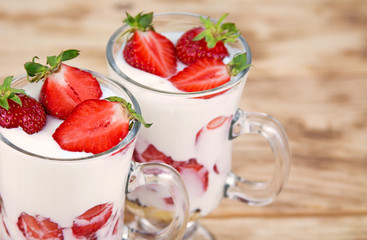 Close up tasty sweet dessert with yogurt and fresh strawberry on a rustic background