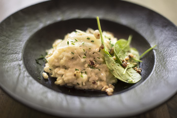 Risotto with gem fit and levisticum celery on a wood table composition
