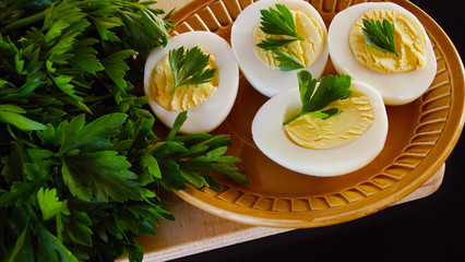 Delicious boiled eggs and parsley on black background.