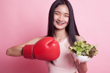 Young Asian woman with boxing glove and salad.