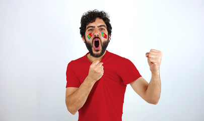 Sport fan screaming for the triumph of his team. Man with the flag of Portugal makeup on his face and red t-shirt.