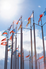 Fototapeta na wymiar Flags of European states on flagpoles against background of cloudy sky.