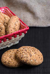 Naklejka premium homemade oat cookies with sunflower seeds in and near red checkered basket on black table