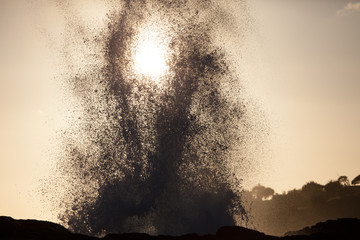 Blowhole on coast of Hawaii silhouetted in the sunset