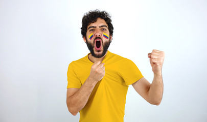 Sport fan screaming for the triumph of his team. Man with the flag of Colombia makeup on his face...