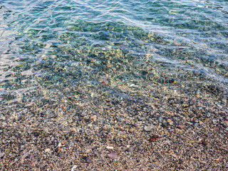 Colorful pebbles under blue sea shallow water texture