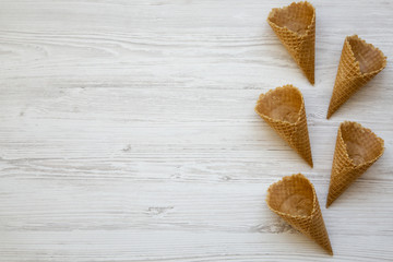 Waffle sweet cones over white wooden background. From above, top view. Copy space.