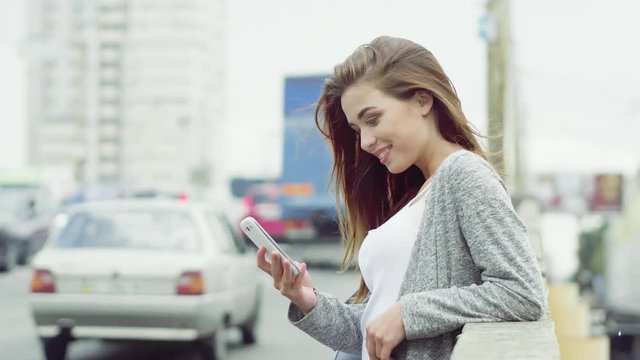 Side view image of wonderful young girl standing near traffic way and reading sms from friend.