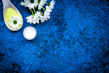 Obraz na płótnie Canvas Natural organic spa cosmetics for skin care with chamomile. Spa salt, oil, cream on blue background top view copy space