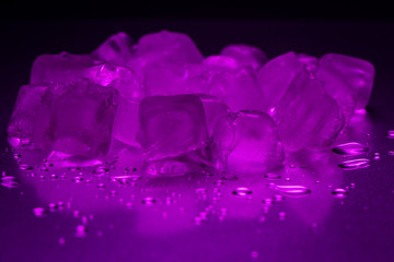 A pile of ice cubes in purple on a reflecting table