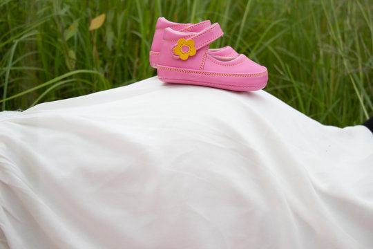 Zapatos rosados en barriga de mama