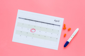 Planning pregnancy. Positive pregnancy test near calendar page and pills on pink background top view copy space