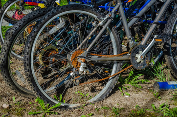 Fototapeta premium Close-up of rear wheel of a rusty deserted biycycle in a crowded blue bike rack