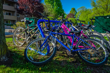 Fototapeta na wymiar Left side view of crowded blue bike rack with dropped and deserted biycycles