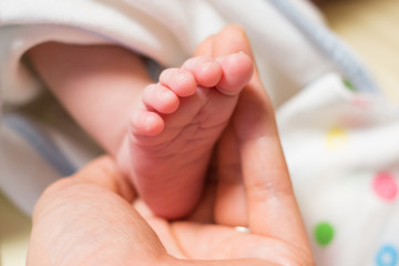 new born baby foot on father's hand