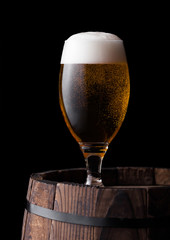 Cold glass of craft beer on old wooden barrel