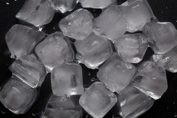 Fototapeta premium Ice cubes on a reflecting table with drops of water on a black background