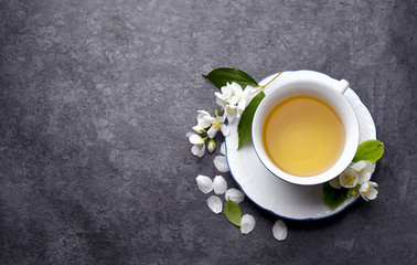Jasmine flowers and cup of healthy tea, herbal medicine. A cup of green tea with jasmine on a black background