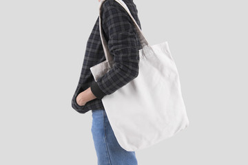Girl is holding bag canvas fabric for mockup blank template isolated on gray background.