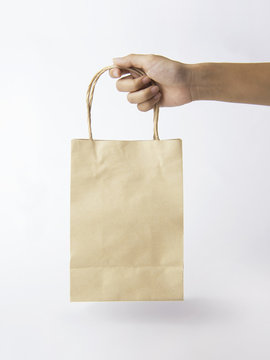 Hand holding Blank brown paper bag for mockup template advertising and branding background.