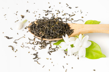 Jasmine green tea in wood spoon with jasmine flower on white background, fresh whole loose leaves, floral flavour for beverage enjoyment during tea time or meal