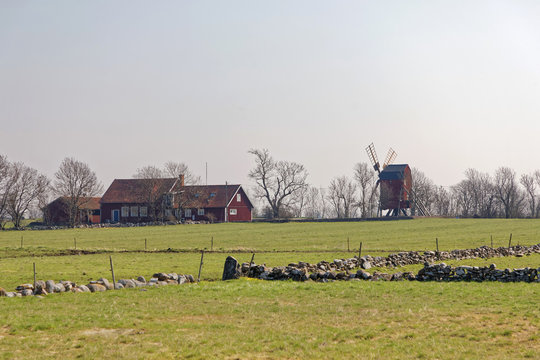 Windmill and traditional rural red building and pasture with green grass outside the city Borgholm at the island Oland in Sweden
