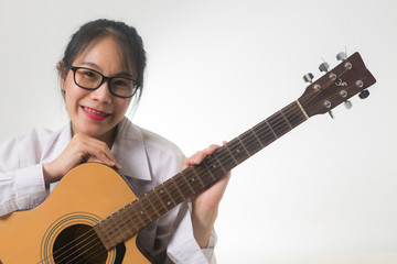 Fototapeta premium Young Asian woman sitting and hug a guitar on white background. Smiling , singing and happiness