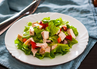 fresh vegetables salad with chicken and onion, lettuce, tomato in white plate on table